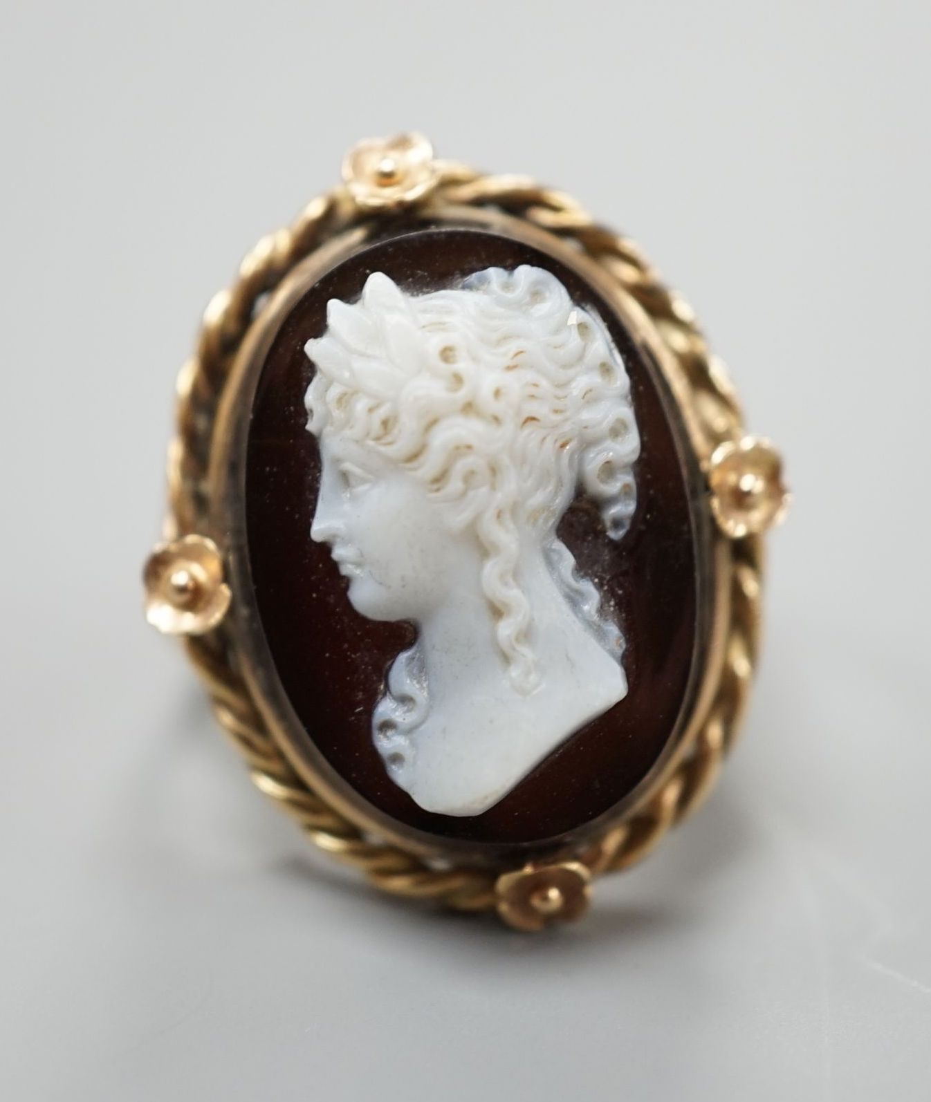 A yellow metal and oval hardstone cameo set dress ring, carved with the bust of a lady to dexter, size M, gross weight 7 grams.